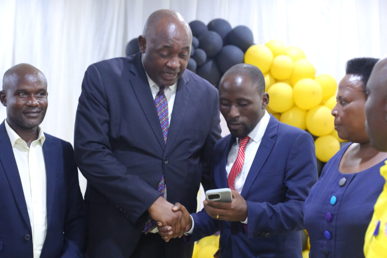 Honourable Baryomunsi shaking hands with Ashaba Vincent